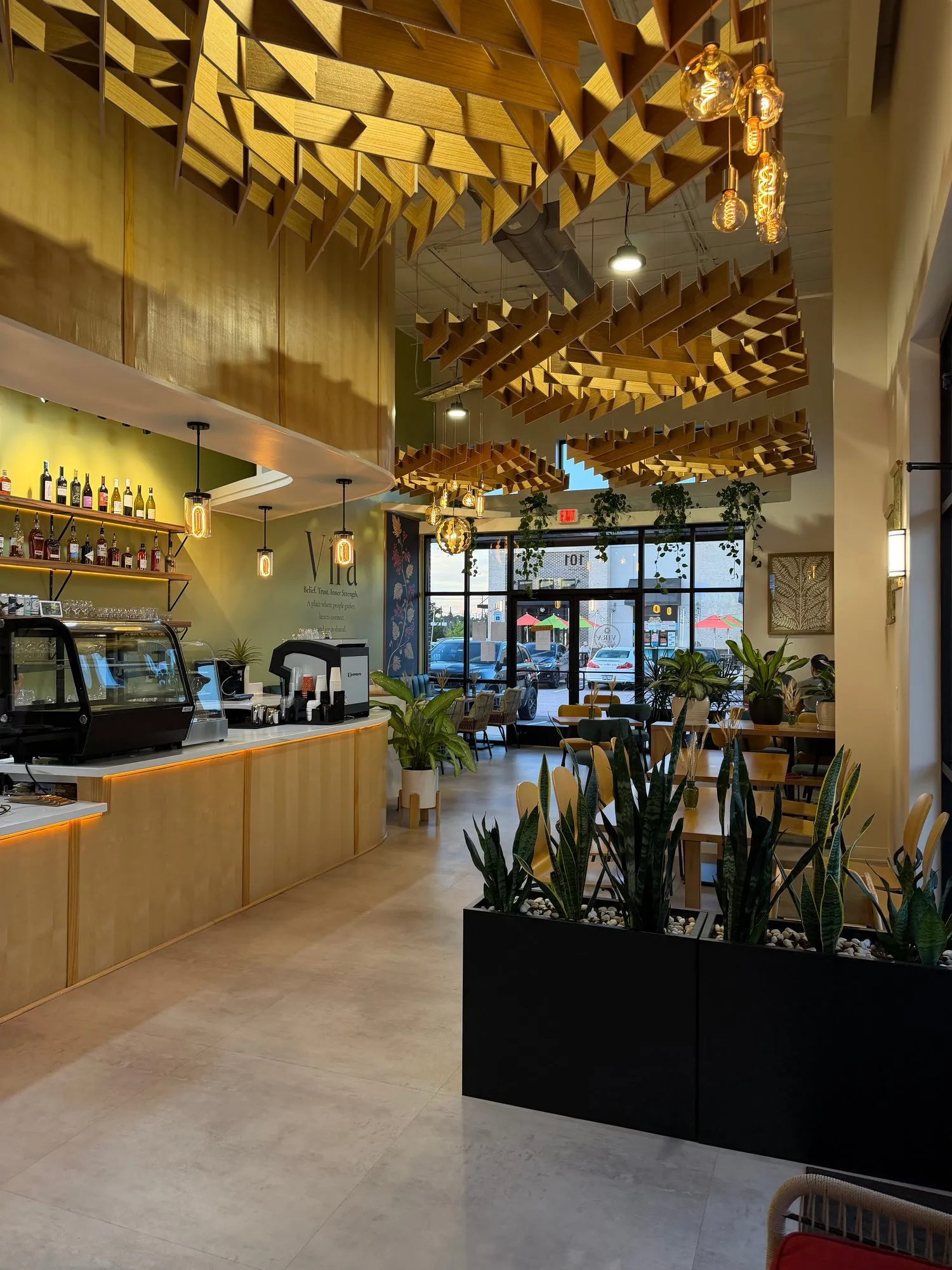 The bar and dining room at Vira Bistro under the wooden ceiling, the front windows at dusk